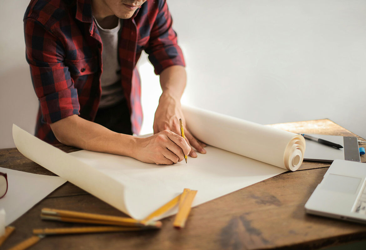 Man drawing building plans on paper